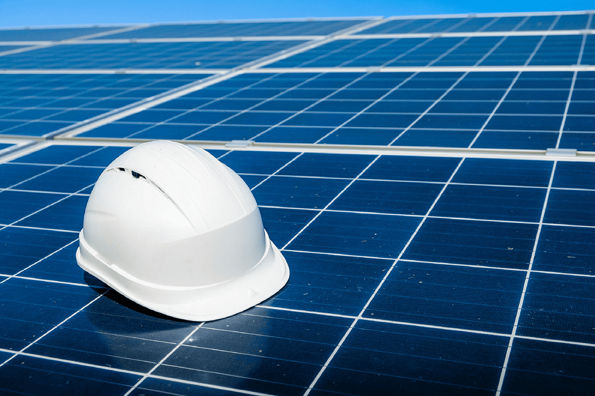 casco blanco de ingeniero apoyado sobre paneles solares